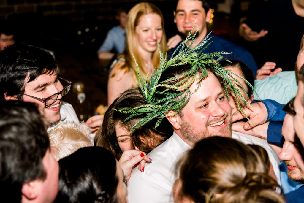 The final song of the night, the groom, celebrating with his closest friends and family, was crowned with greenery from the centerpieces.