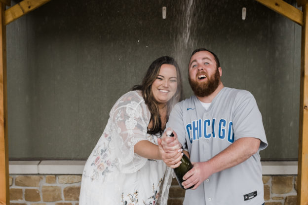 Wedding photographer capture images of bride and groom spraying champagne at the rehearsal dinner.