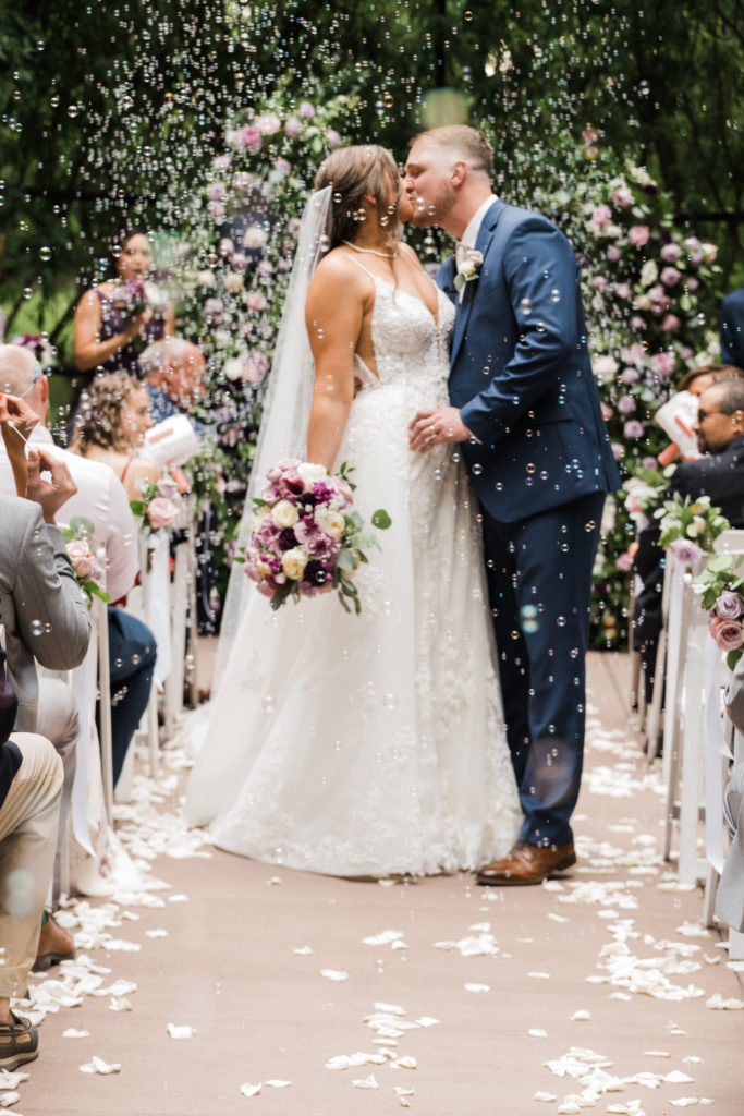 Bride and groom kiss in the aisle Black Iris wedding Carmel, Indiana